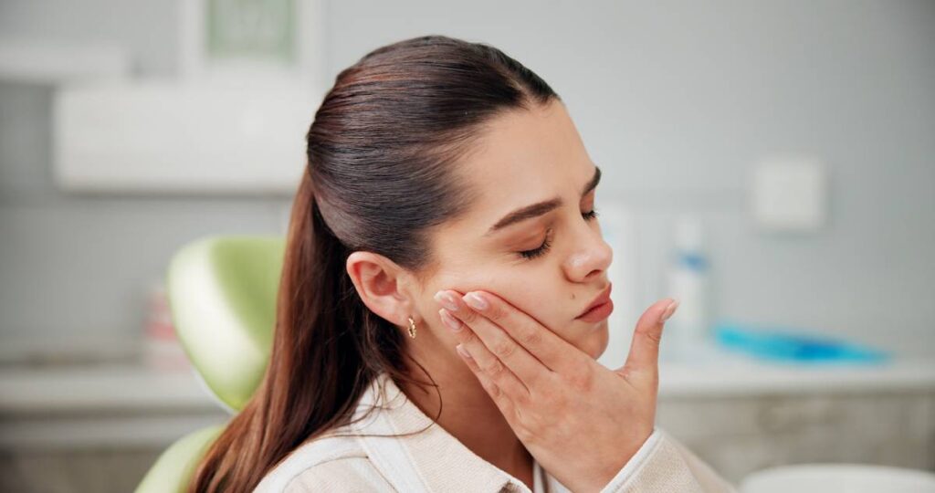 Woman with pain in her mouth due to swollen gums toothache and stress in dentist chair for pain, cavity or rotten tooth at oral care clinic. Person, patient and gum disease with inflammation, infection or frustrated at dental health hospital.